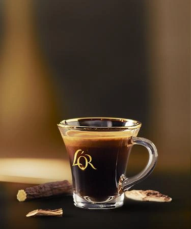 Two mugs filled with L'OR Espresso on a slate tray, with scattered coffee beans and a silver spoon for an elegant presentation.
